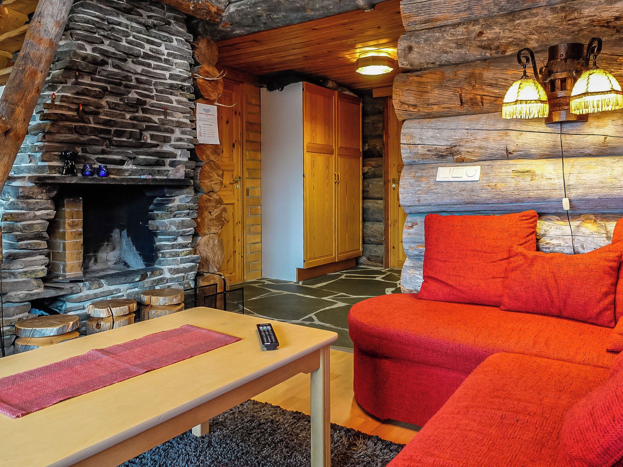 Un interior acogedor con chimenea de piedra, mobiliario de madera y un sofá rojo.