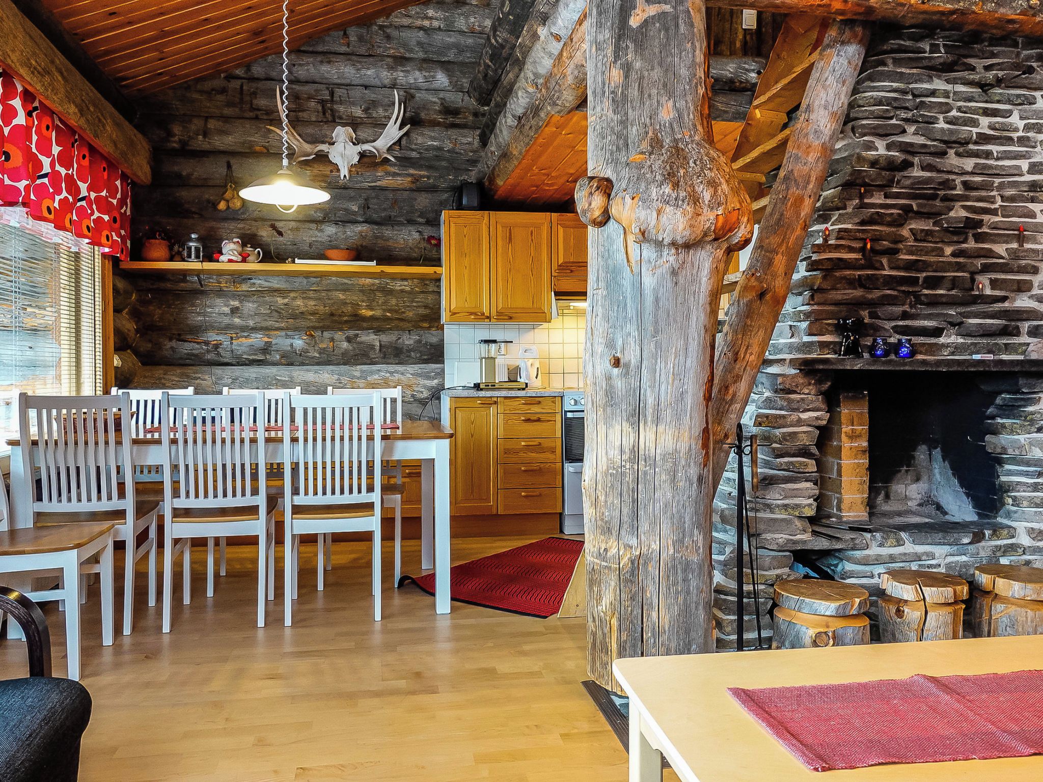 A rustic interior with a wooden dining area, a stone fireplace, and a kitchen with wooden cabinets.