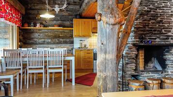 A rustic interior with a wooden dining area, a stone fireplace, and a kitchen with wooden cabinets.