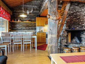 Un interno rustico con una zona pranzo in legno, un camino in pietra e una cucina con mobili in legno.