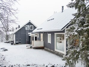 A two-story house with a snow-covered roof and a porch.
