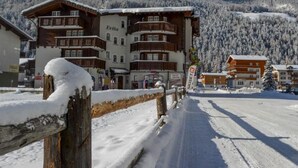Eine verschneite Bergstadt mit hölzernem Zaun und Häusern mit Balkonen.