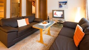Ein gemütliches Wohnzimmer mit einer Couch, einem Couchtisch und einem Fernseher.