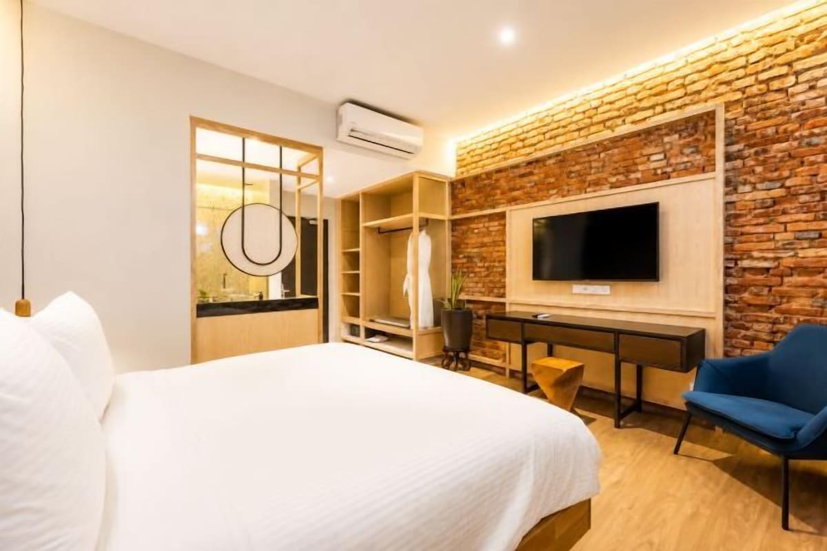 A hotel room with a bed, a desk, a chair, a TV, and a wardrobe.