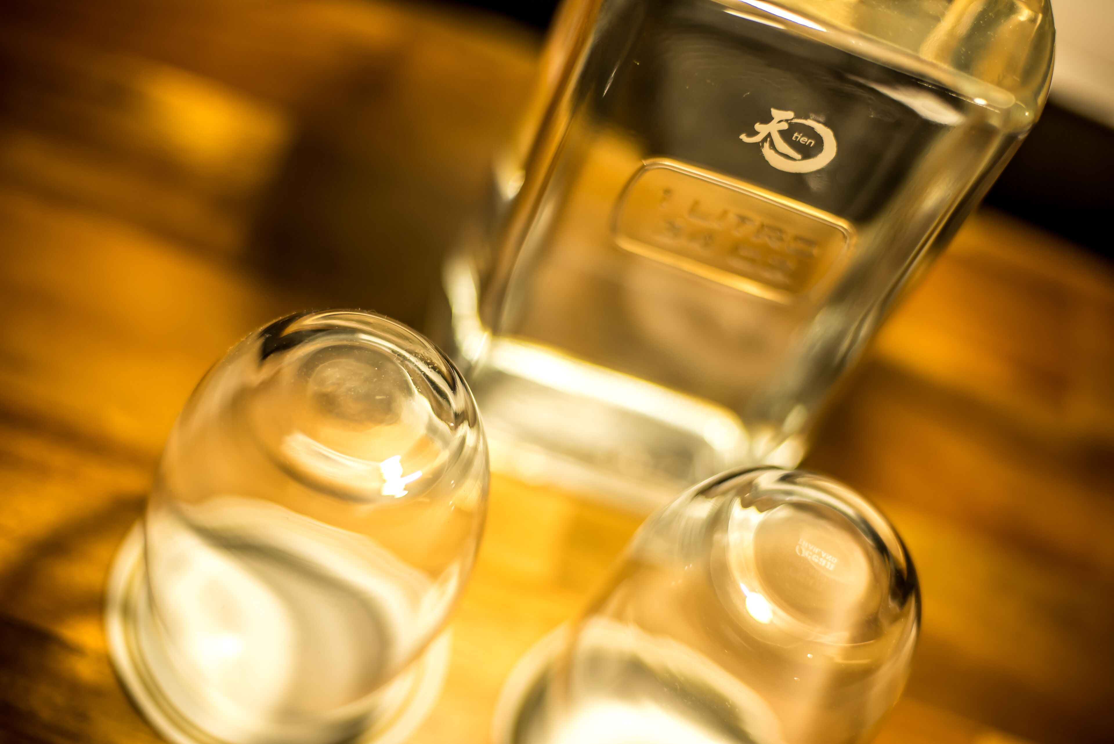 A close-up of two clear glass bottles with a label on one, placed on a reflective surface.