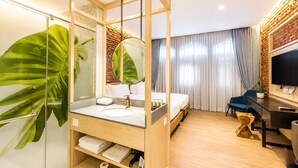 A modern hotel room with a wooden bed, a large mirror, a bathroom with a glass shower enclosure, and a TV. - Tien Terrace (George Town)