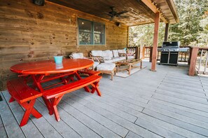 Eine Holzterrasse mit einem roten Picknicktisch und einem Grill.