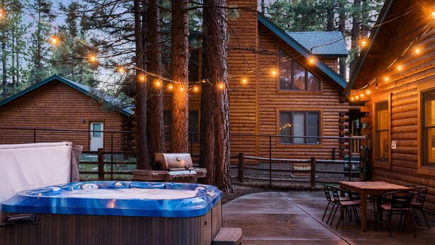En træhytte med jacuzzi, grill og udendørs siddeplads.