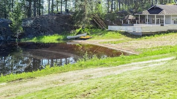 En fastighet vid en sjö med en brygga, ett hus med en veranda och ett skogsområde.