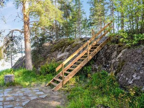 En trätrappa som leder uppför en brant, stenig sluttning, med en stenlagd stig vid foten.