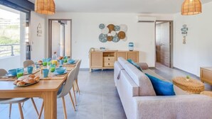 Una sala de estar moderna con comedor, que incluye un sofá, una mesa de centro y una mesa de comedor dispuesta con alimentos para el desayuno.