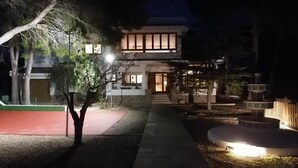 A two-story building with a well-lit entrance and a small garden area with a fountain.