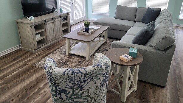 A living room with a sofa, a coffee table, a TV, and a cabinet. - Ocean View, Short Walk to Beach, Free Golf Cart Included (Port Aransas)