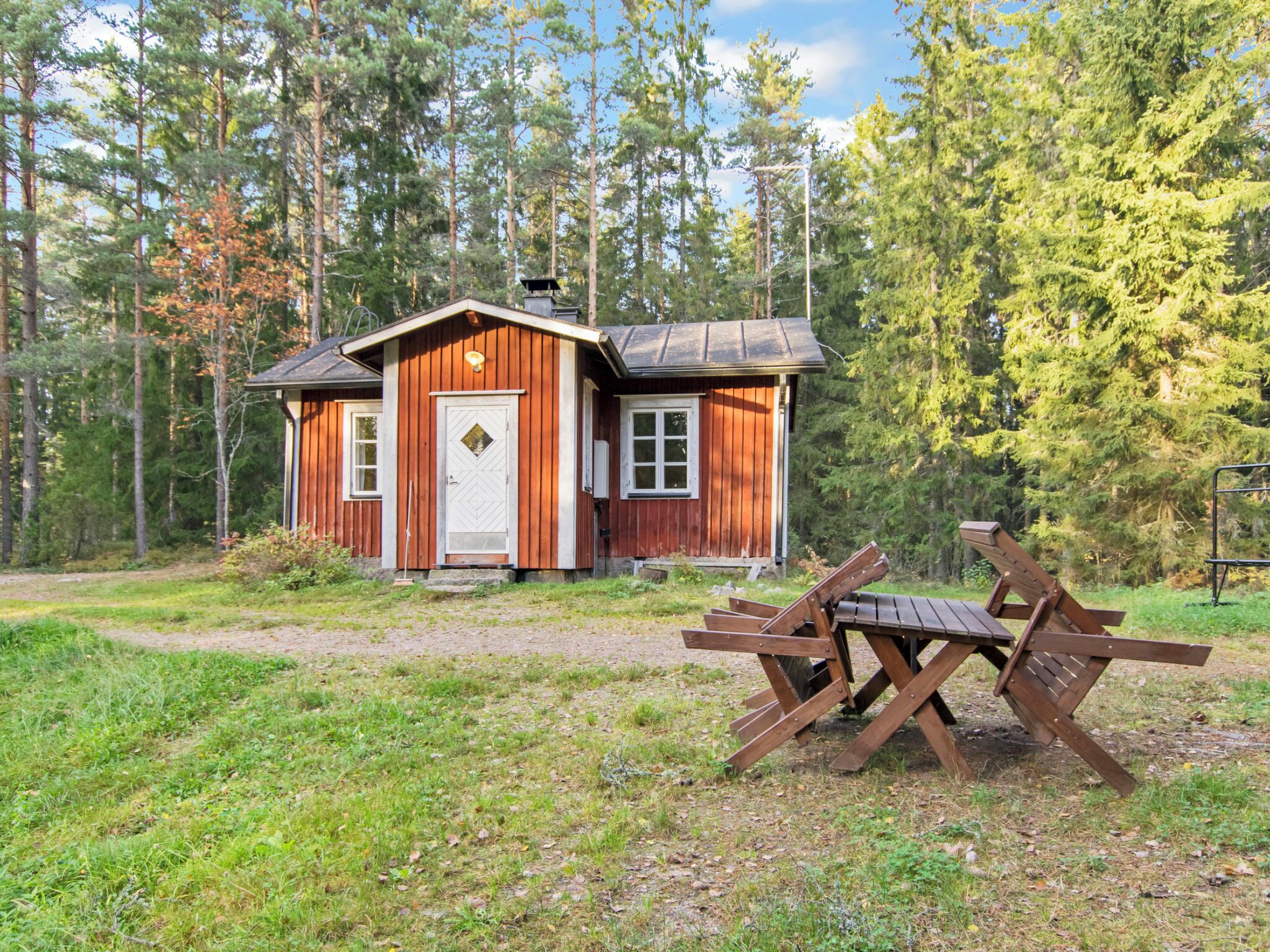 Eine Holzhütte mit weißer Tür und Fenstern, umgeben von einem Wald.