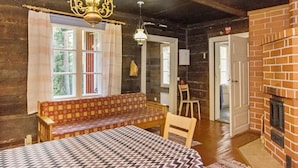 Een rustieke houten kamer met een bank, een tafel, een open haard en een kroonluchter.