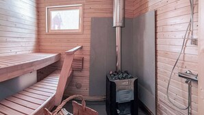 Een sauna met houten banken, een sauna-oven en een doucheruimte.
