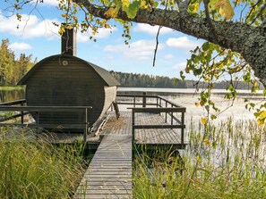 Une structure en bois avec une jetée menant à un plan d’eau, le tout entouré d’arbres et de végétation.