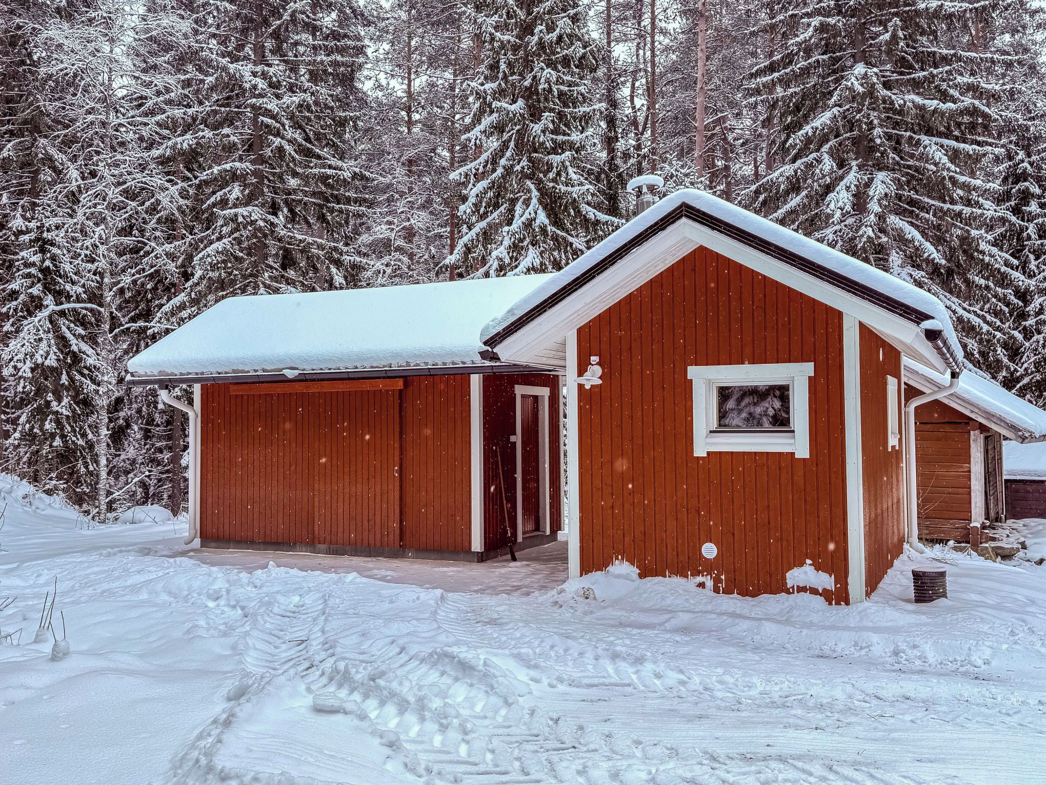 Eine Holzhütte mit verschneitem Dach und einer Garage.