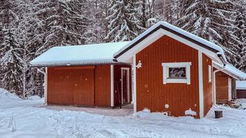 Eine Holzhütte mit verschneitem Dach und einer Garage.