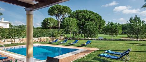 A pool area with lounge chairs and a table set for dining.
