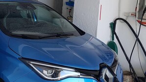 Un coche azul estacionado en el interior, con mangueras y un enchufe a la vista.