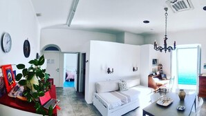 Una habitación amplia con cama, zona de comedor y vista al mar.