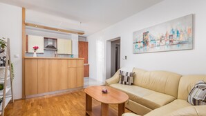 A modern living room with a beige sofa, a wooden coffee table, and a cityscape painting on the wall. - Apartment L and M - discover Matulji (Matulji)