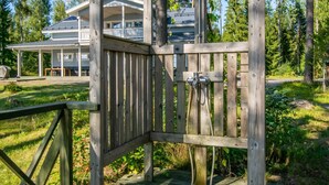 Een houten terras met een metalen hek dat leidt naar een huis met een overdekte patio en een zwembad.