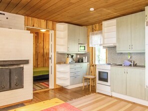 Una cucina compatta con mobili in legno, un forno a microonde, un piano cottura e un'area pranzo con una sedia.
