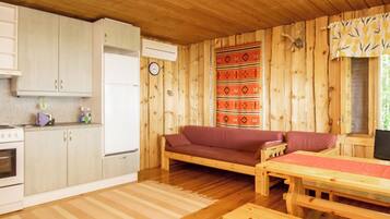 A cabin interior with a kitchenette, a sofa, a dining table, and a patterned wall.