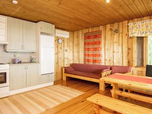 A cabin interior with a kitchenette, a sofa, a dining table, and a patterned wall. - Isokoskelo by Interhome (Pertunmaa)