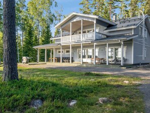 A two-story house with a porch and outdoor seating area. - Isokoskelo by Interhome (Pertunmaa)