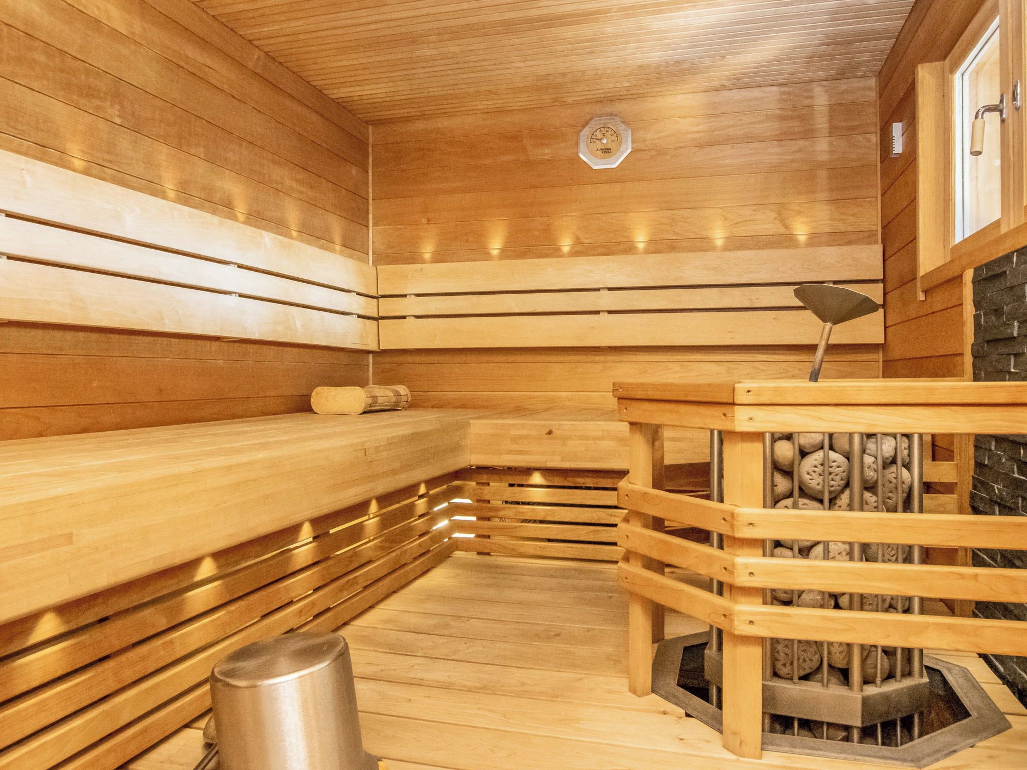 Una sauna con bancos de madera, pared de piedra y calentador.