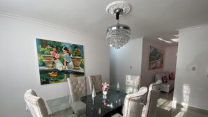 Ein Essbereich mit einem Glastisch, gepolsterten Stühlen, einer Kandelaber und einem Gemälde an der Wand.