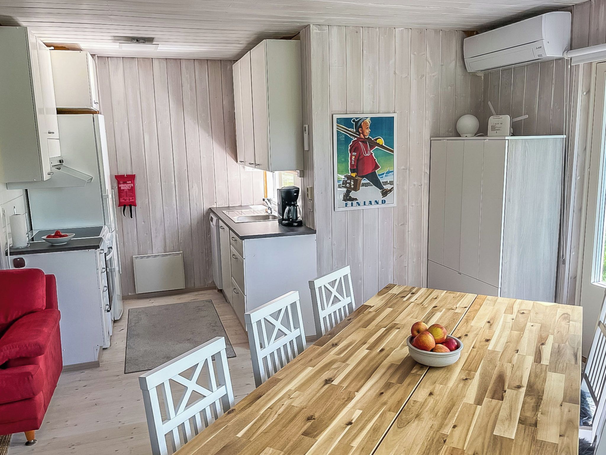 A compact kitchen with white cabinets, a coffee maker, and a poster on the wall.