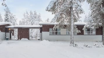 A snow-covered building with a garage and a covered driveway.