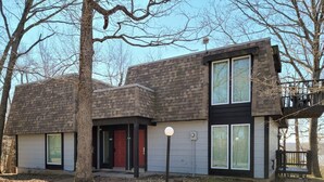A modern two-story house with a flat roof, large windows, and a red door. - Anchors Away - Three Bedroom House, Sleeps 12 (Osage Beach)