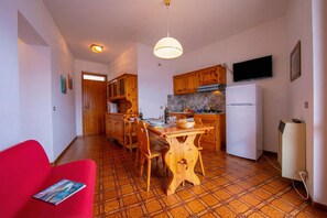 Une cuisine de taille réduite avec des meubles en bois, une table à manger et un canapé rouge.