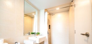 Ein modernes Badezimmer mit Waschbecken, Spiegel und Duschbereich.