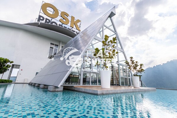 Ein modernes Hotel mit Poolbereich, einem gut sichtbaren 'Osk'-Schild und einem Berg im Hintergrund.