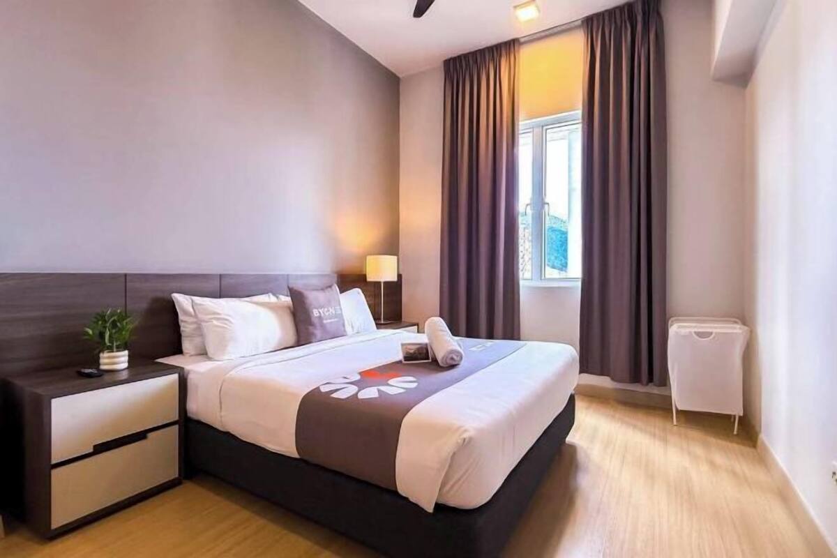 Une chambre d’hôtel moderne avec un grand lit, une table de chevet, une lampe et une vue sur l’extérieur.