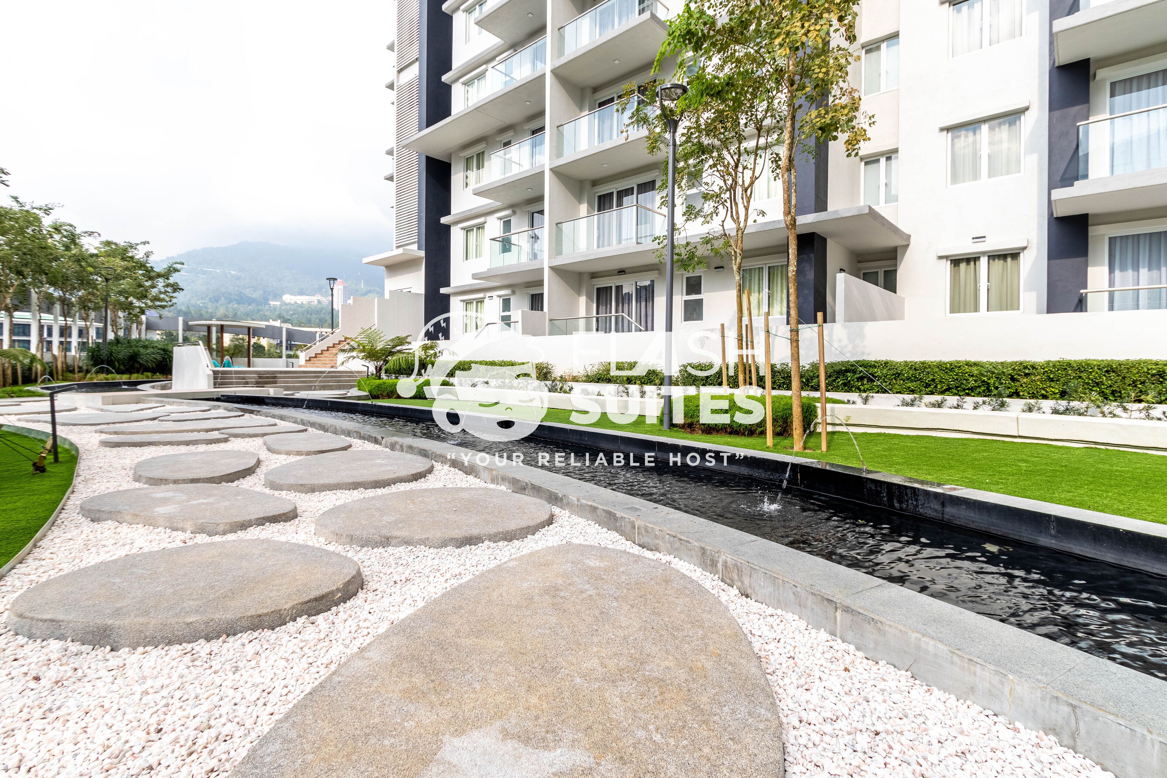 A modern hotel with a pool area, stone steps, and a well-maintained lawn.
