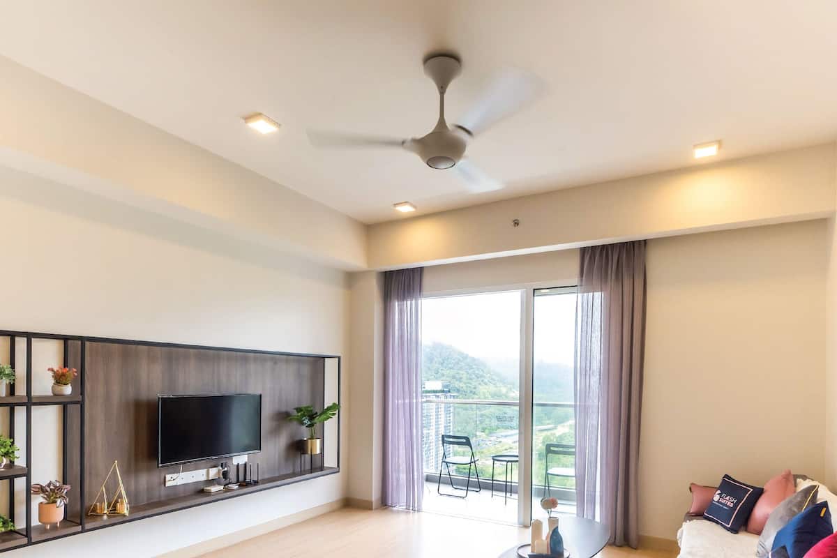 Un salon moderne doté d’un téléviseur à écran plat, d’un ventilateur de plafond et d’un balcon avec des meubles d’extérieur.