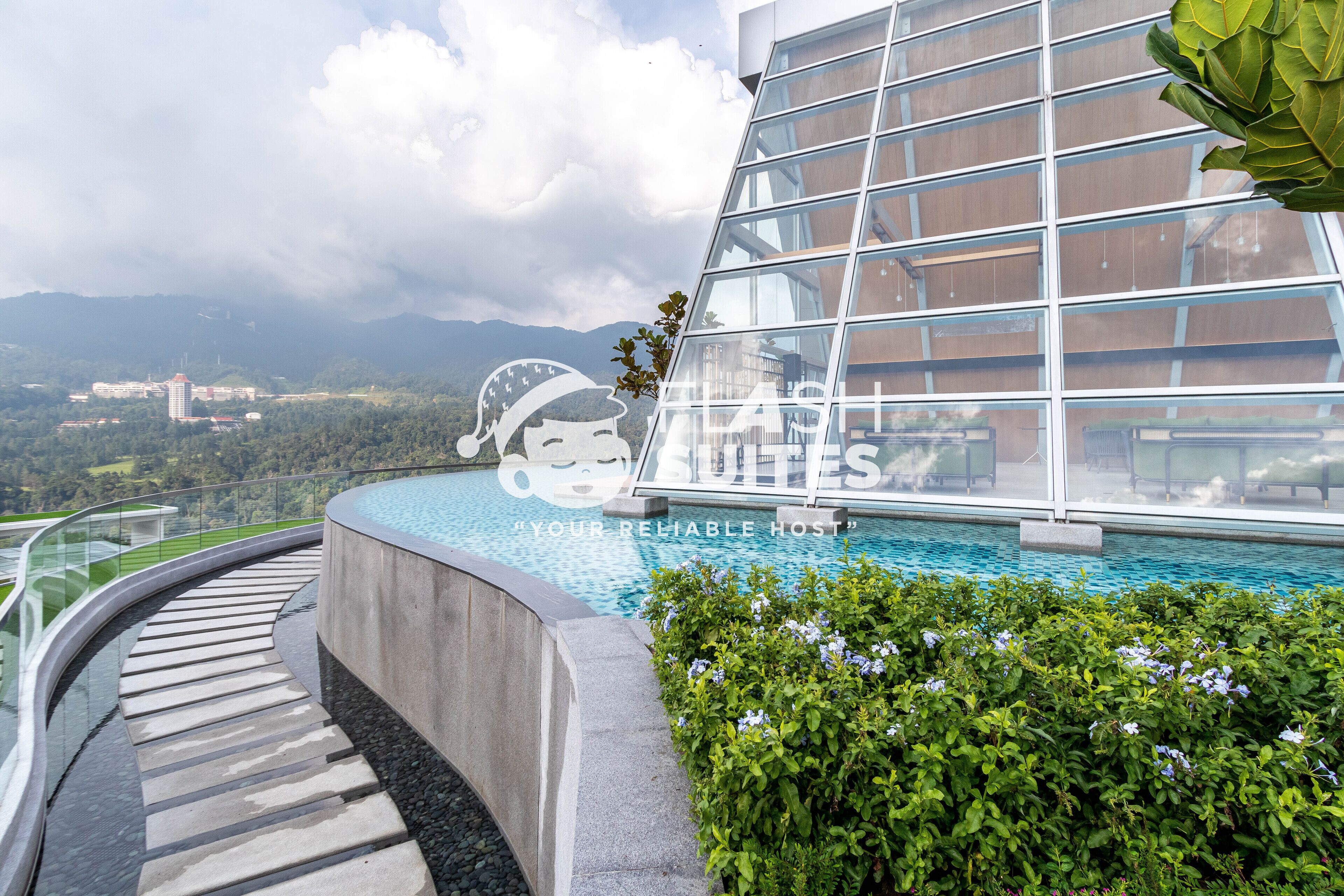 A modern hotel with a glass facade, a pool, and a view of mountains.