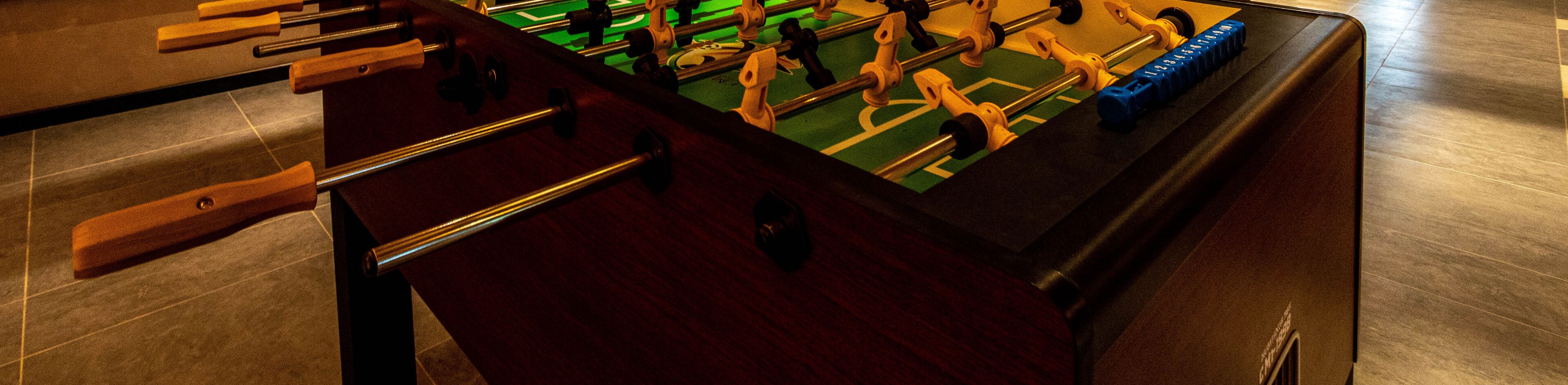 A close-up of a foosball table with a green playing surface and metal rods.