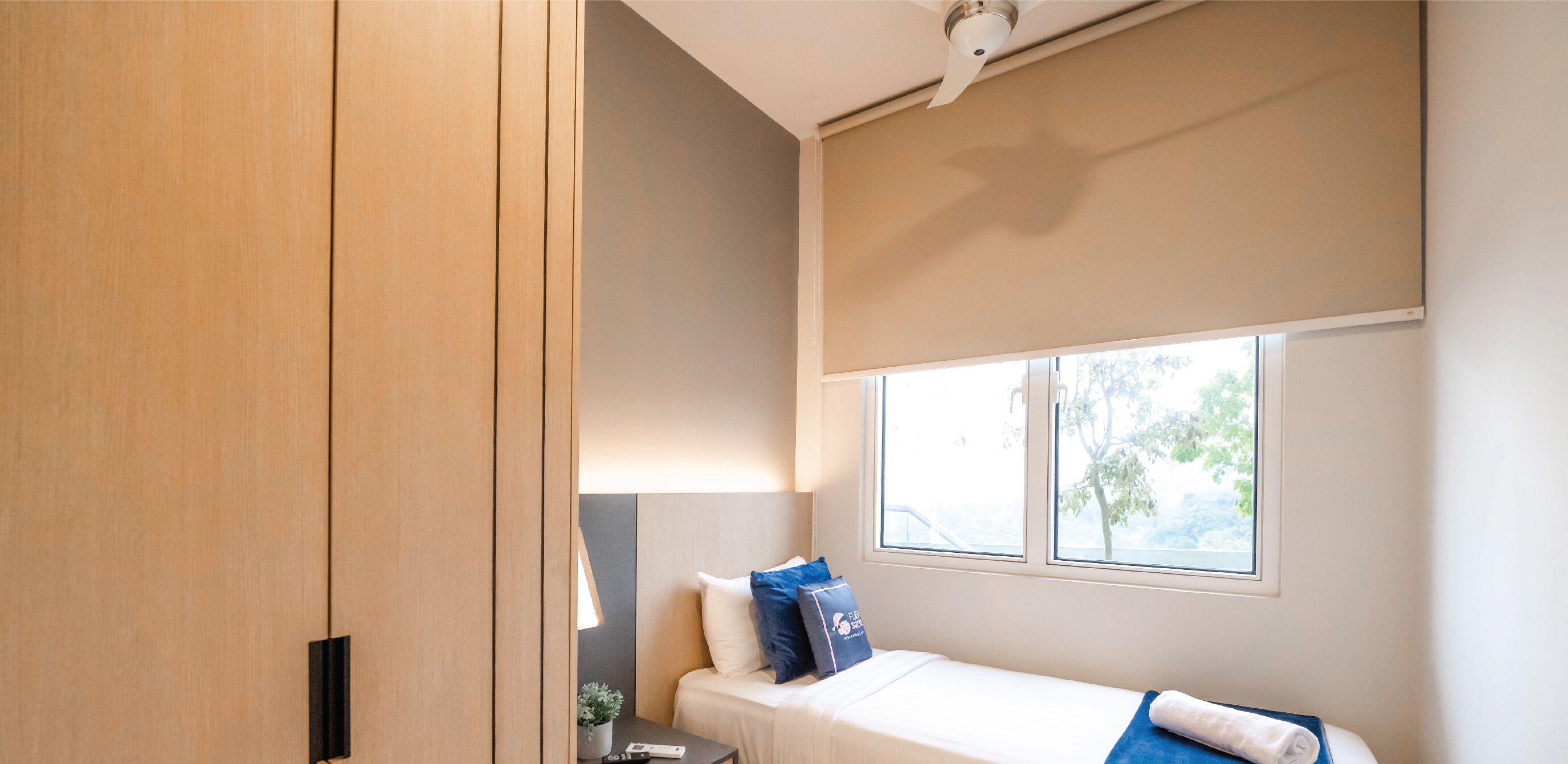 A modern hotel room with a bed, a window, and a ceiling fan.