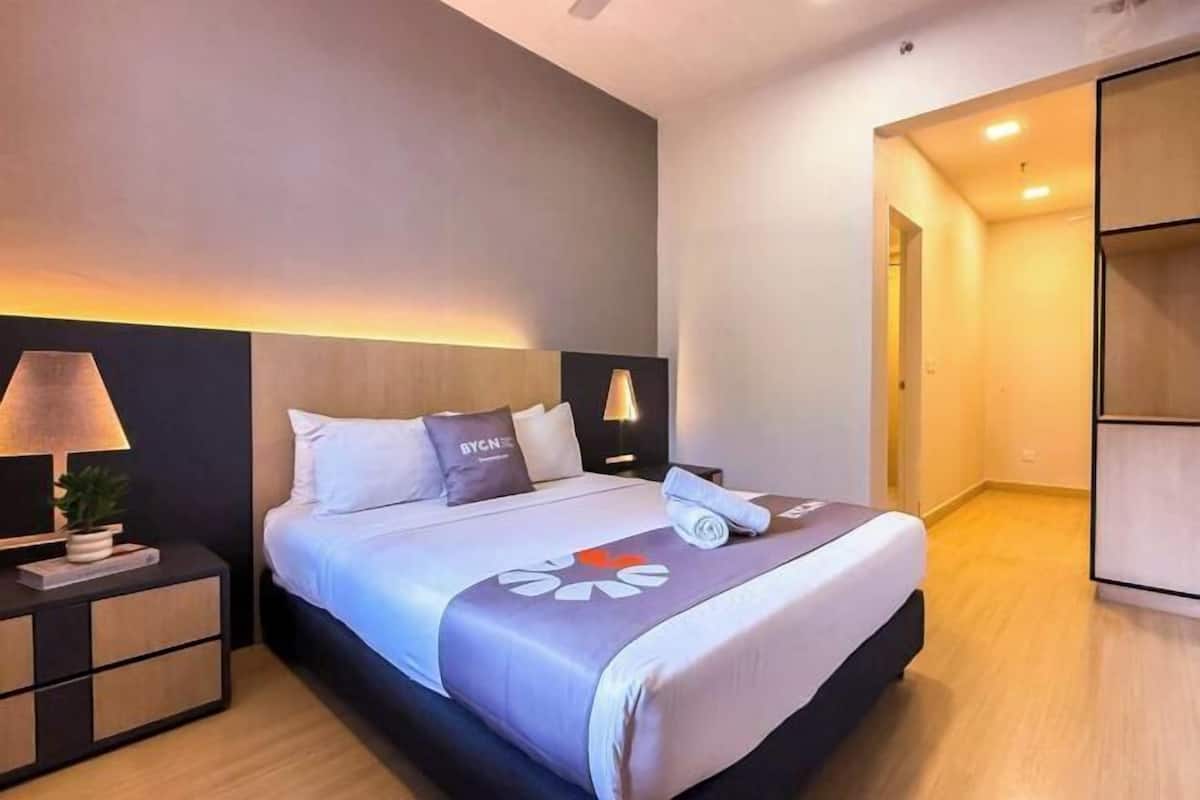 Une chambre d’hôtel moderne équipée d’un lit, de tables de chevet, d’une lampe et d’une armoire.