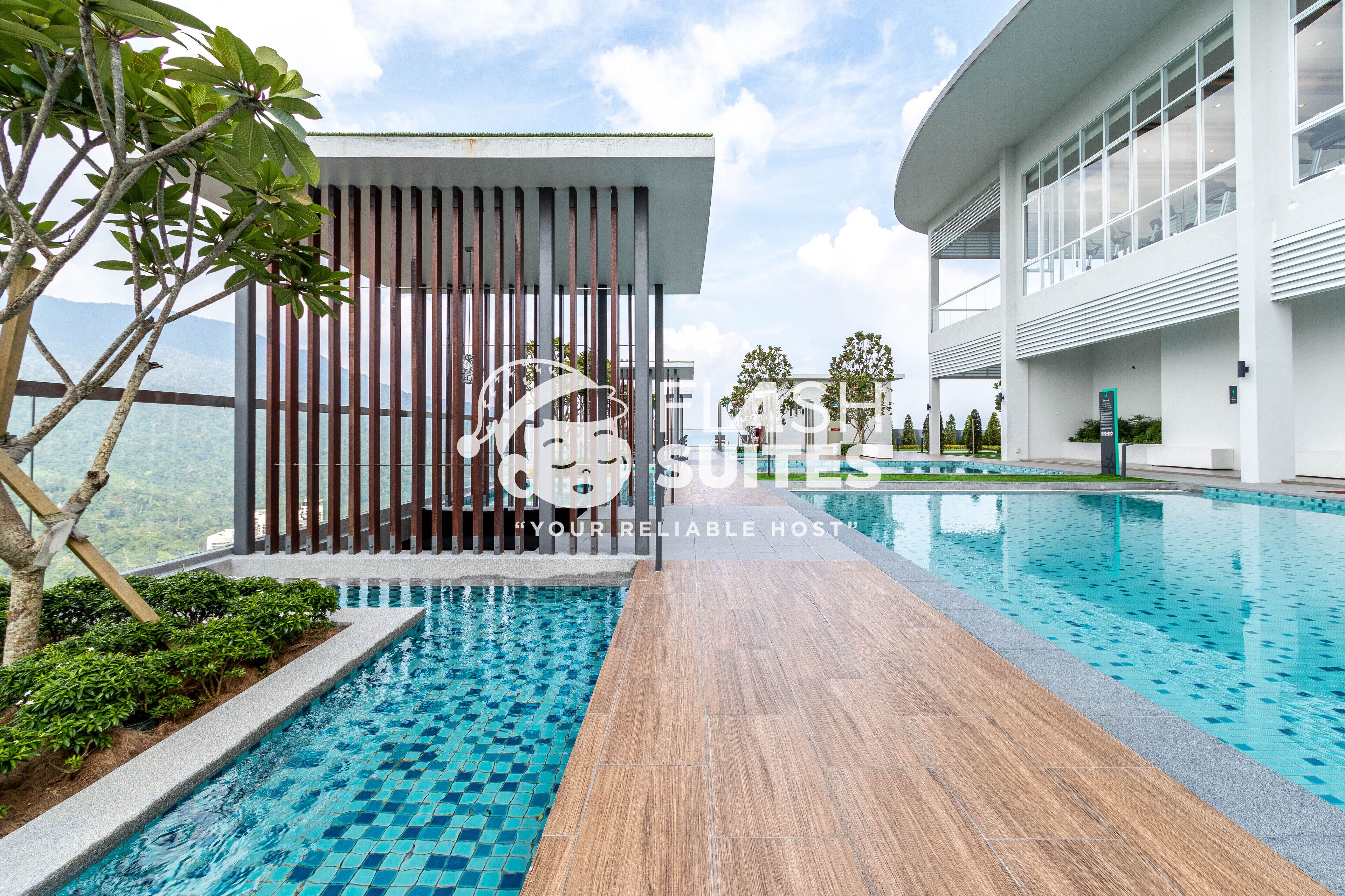 A modern hotel with a swimming pool, a wooden deck, and a view of the mountains.