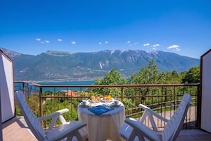 A balcony with a table set for breakfast, overlooking a mountainous landscape and a body of water. - Appartamento Secrel 10, Tremosine, Italy (Tremosine)
