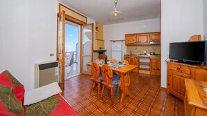 A compact living space with a dining area, kitchenette, and a TV. - Appartamento Secrel 9, Tremosine, Italy (Tremosine)